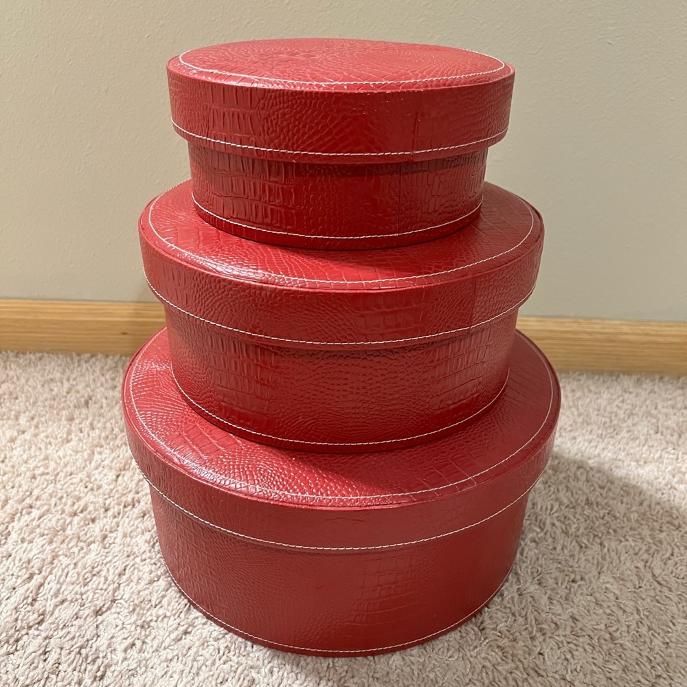 Three red, faux croc leather round nesting boxes, black felt lined inside.